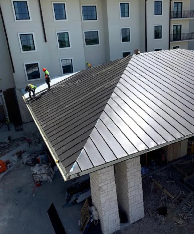 Crew installing standing seam metal roof panels on a commercial project in Dundee